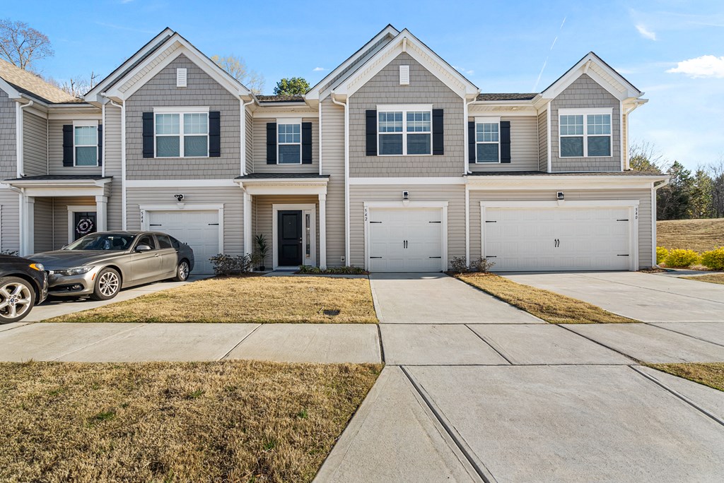 A grey house with a silver car parked in front.