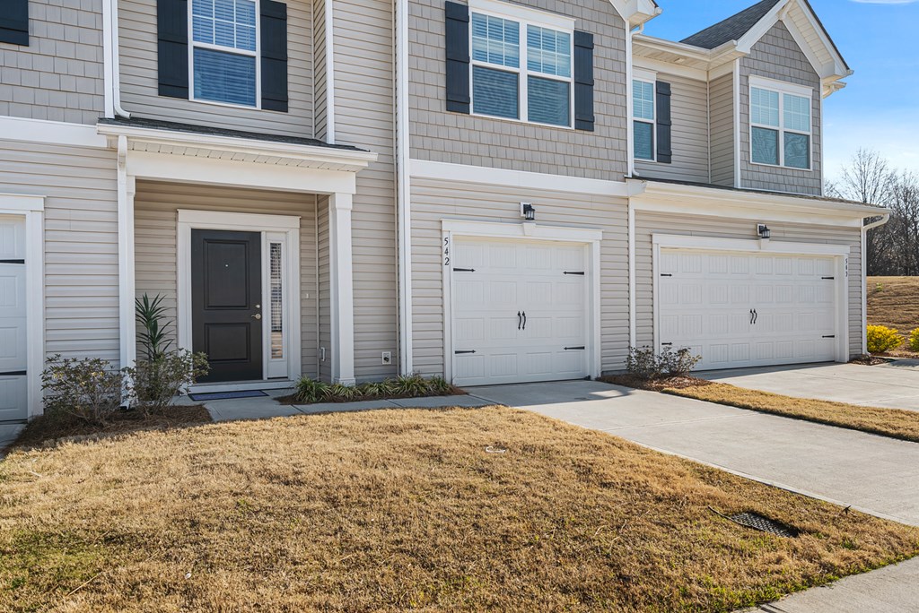 A two-story house with a garage door and a driveway.
