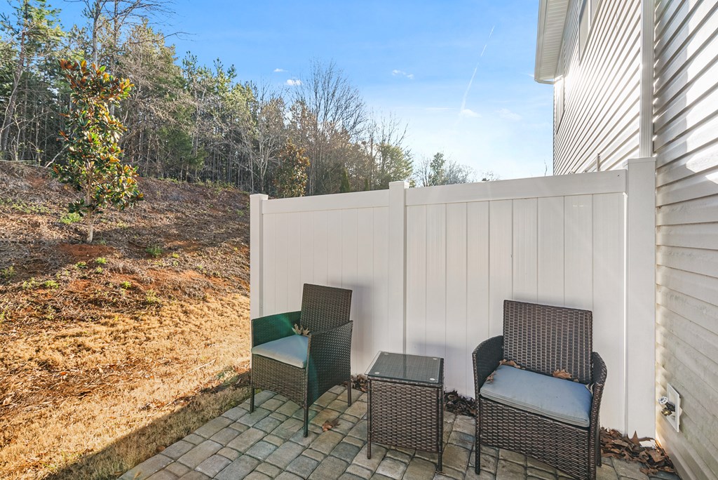 A patio with a white wall and two chairs.