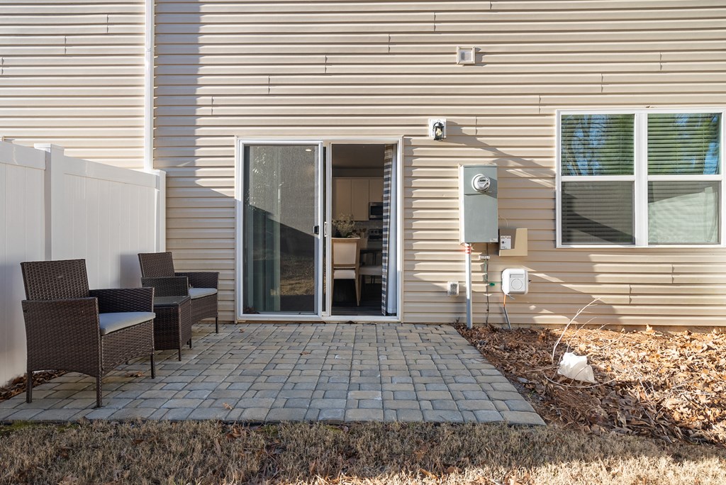 A patio with a table and chairs is in front of a house.