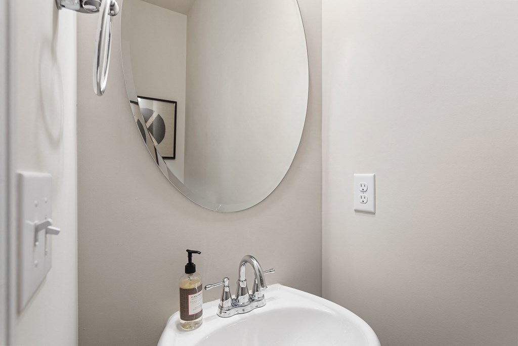 A white sink with a soap dispenser and a mirror above it.