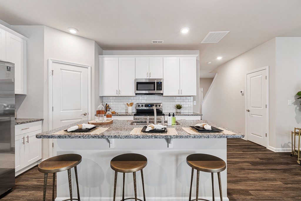 A kitchen with white cabinets and a granite countertop.