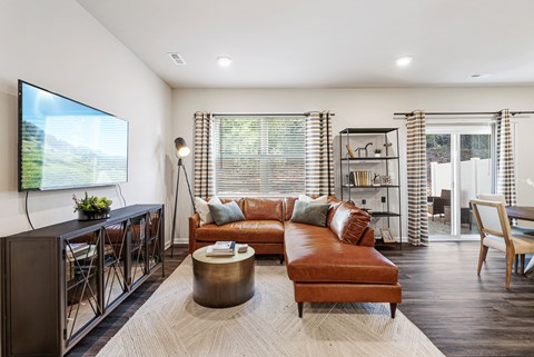 A living room with a brown leather couch and a television on the wall.