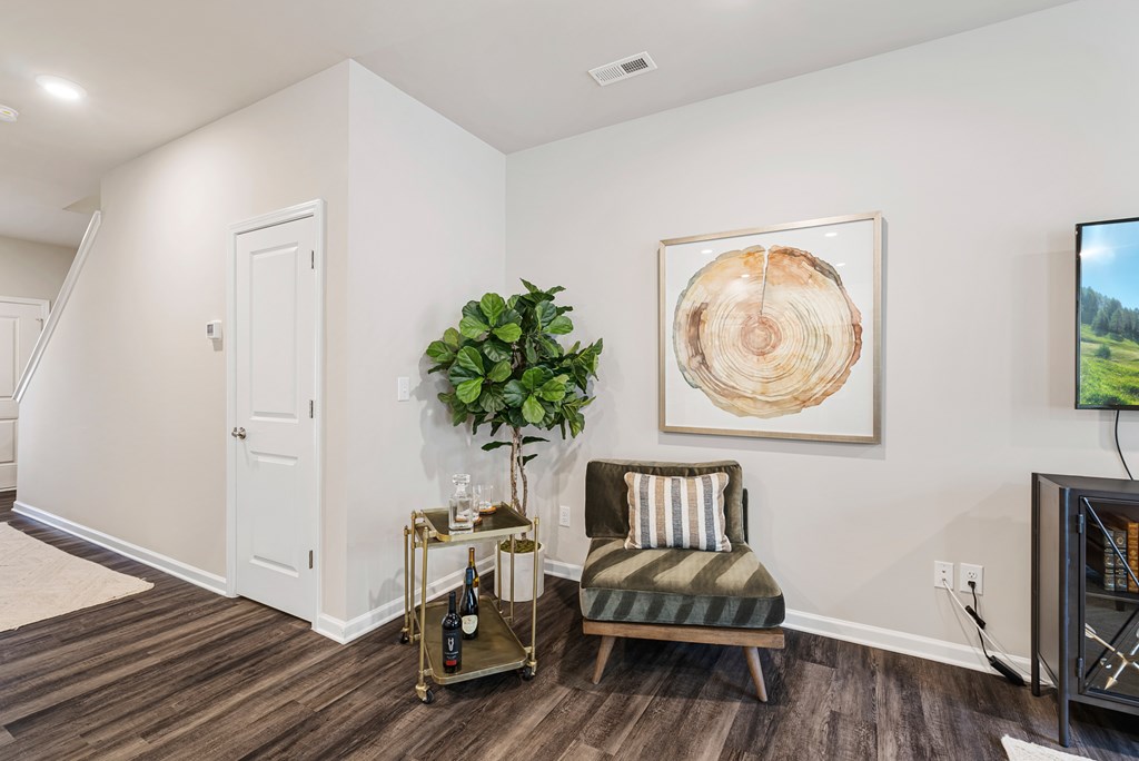 A living room with a chair, a plant, and a painting on the wall.