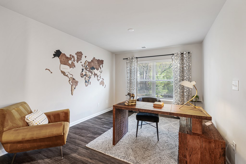 A room with a chair, a table, and a map on the wall.