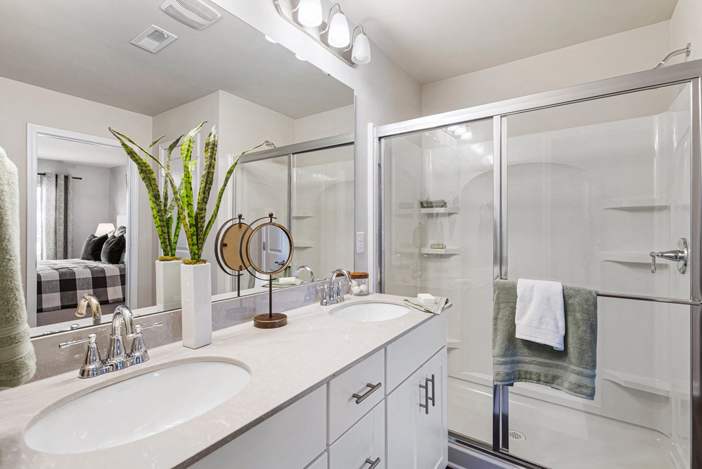 A white bathroom with a sink, mirror, and shower.