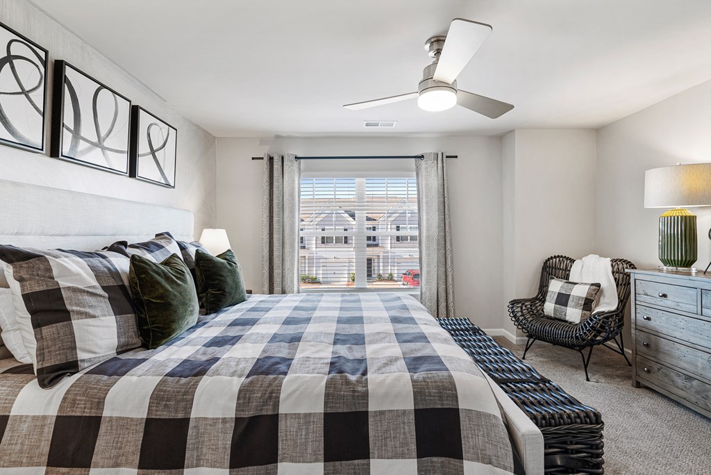 A bedroom with a large bed and a chair by the window.