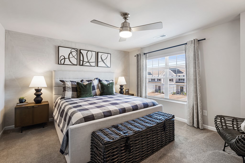 A bedroom with a bed, nightstand, chair, and window.