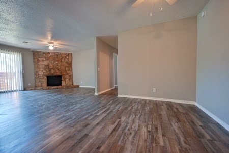 A room with wooden floors and a stone fireplace.