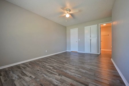 A room with a ceiling fan and wood flooring.