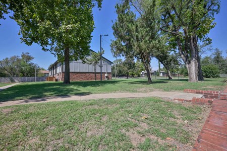 A park with a building in the background and a brick wall on the right.