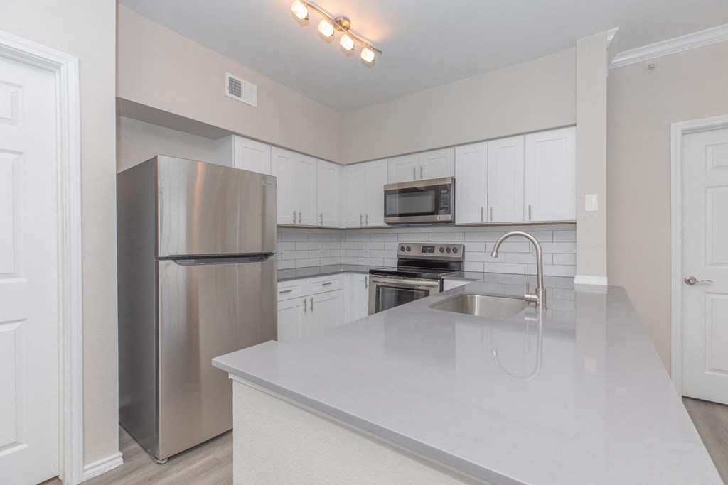 an empty kitchen with a sink and a stainless steel refrigerator