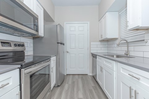 a kitchen with white cabinets and stainless steel appliances