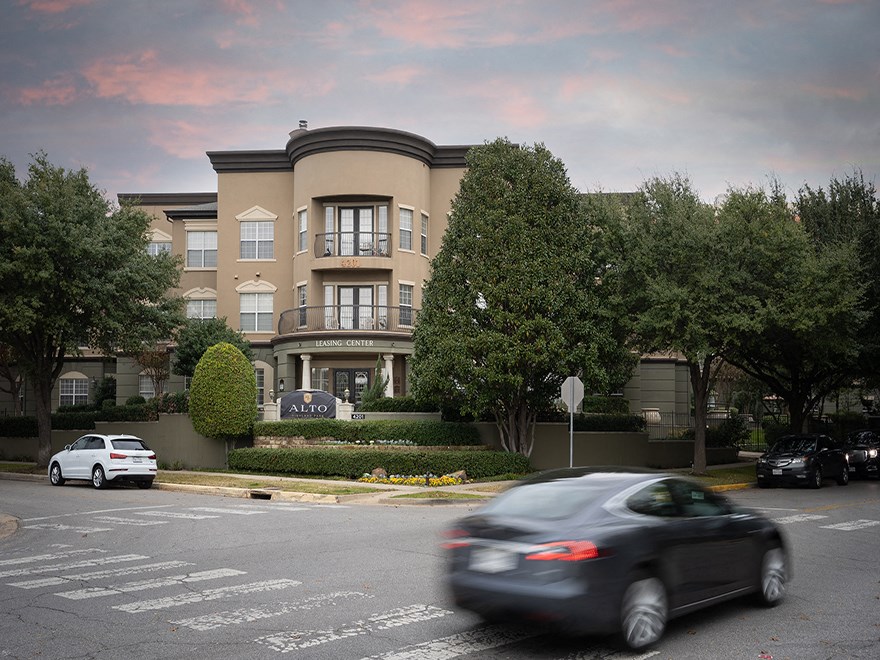 a car drives past an apartment building on a city street