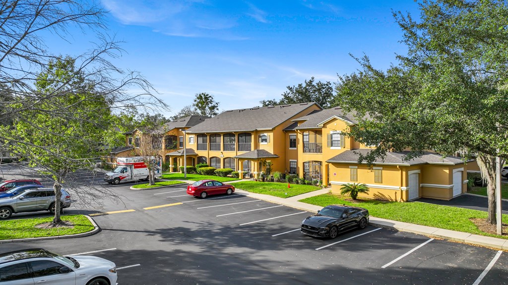 a large yellow house with cars parked in a parking lot