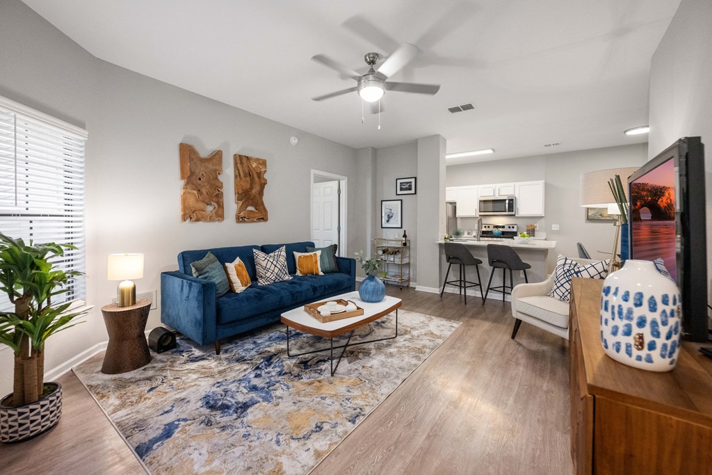 an open living room and kitchen with a blue couch and a ceiling fan