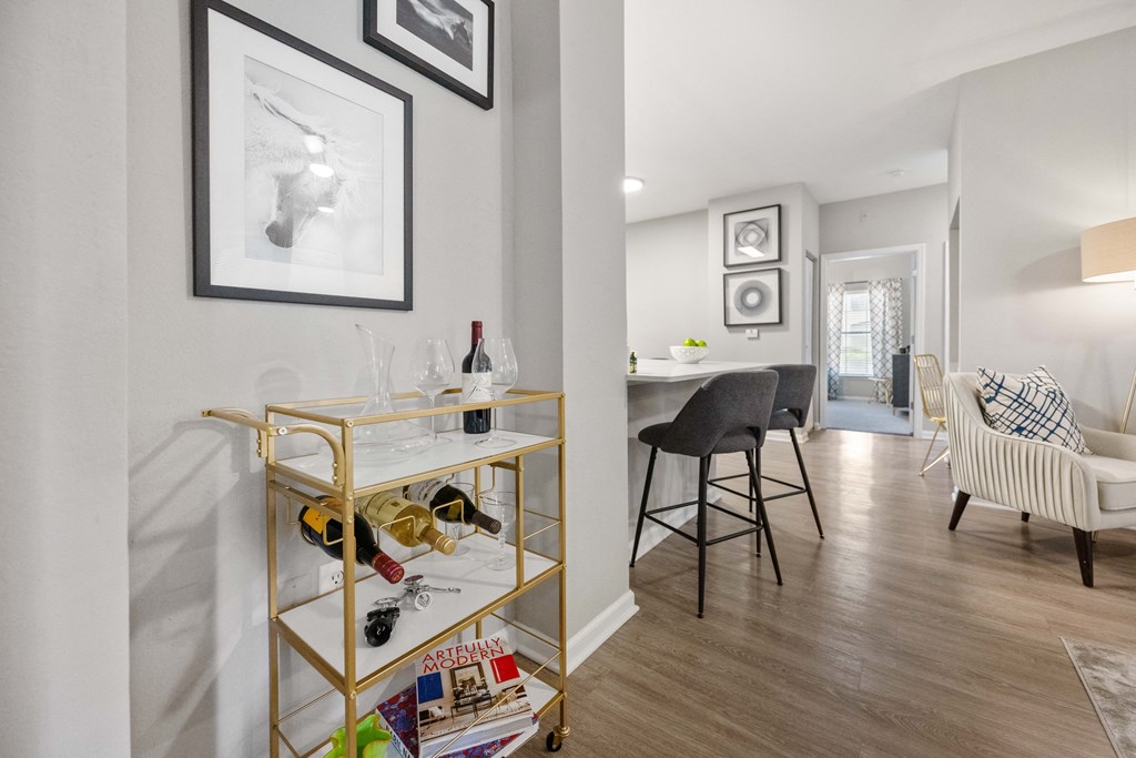 a living room and dining room with white walls and a gold shelf with wine glasses