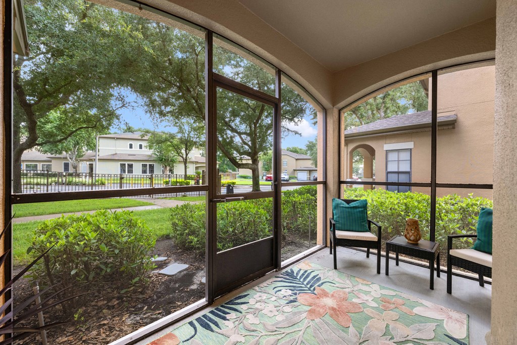 a patio with large windows and chairs and a rug