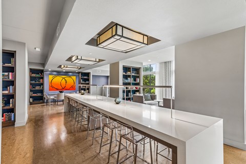 A modern bar area with a long white counter and stools.