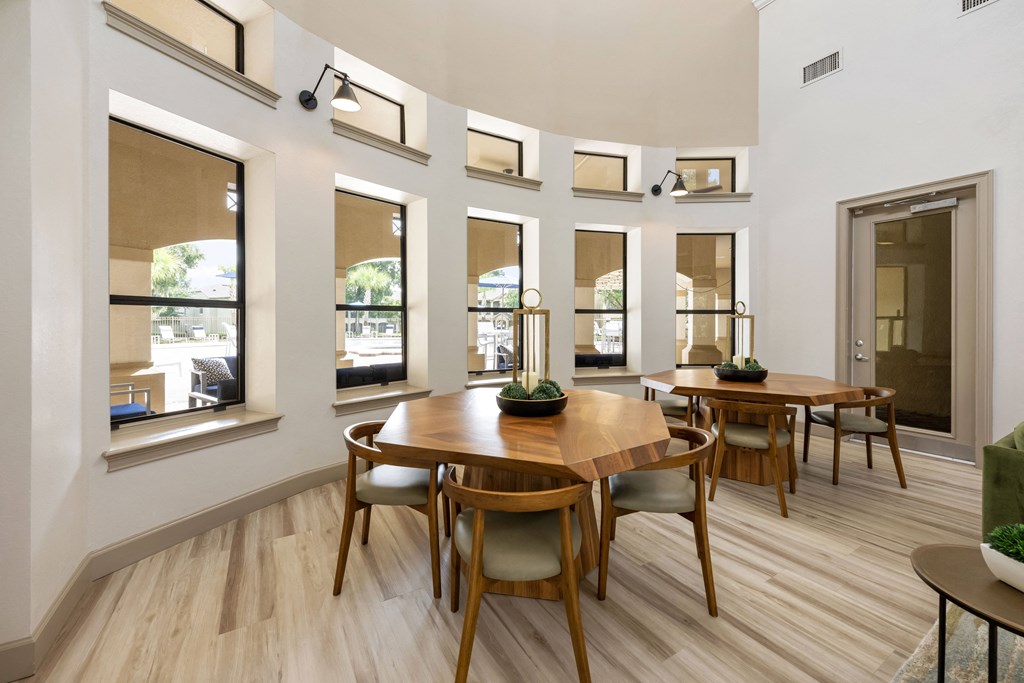 a dining room with a wooden table and chairs and windows