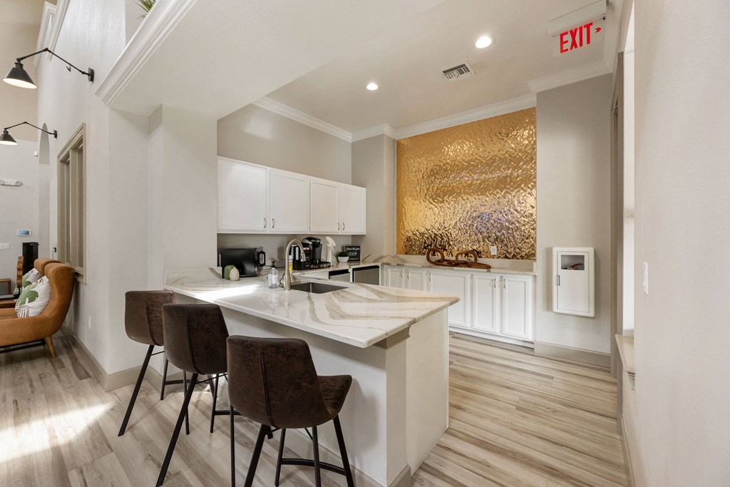 a kitchen with white cabinets and a marble counter top