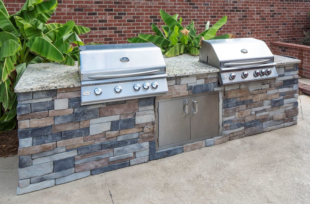 an outdoor kitchen with two grills and stainless steel cabinets