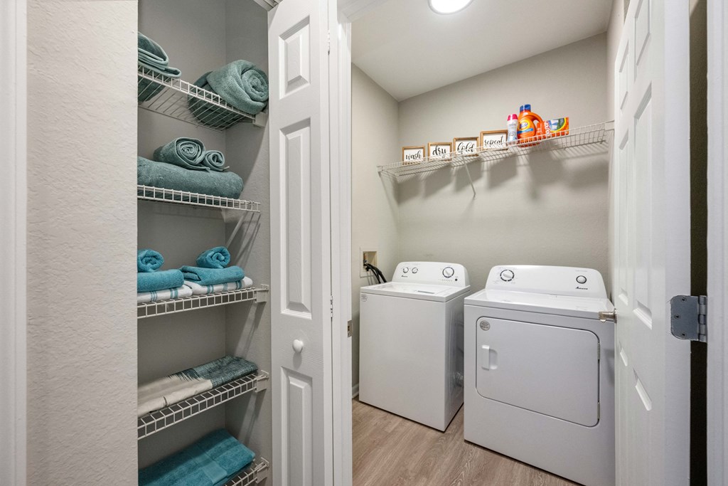 a laundry room with a washer and dryer and a closet with shelves