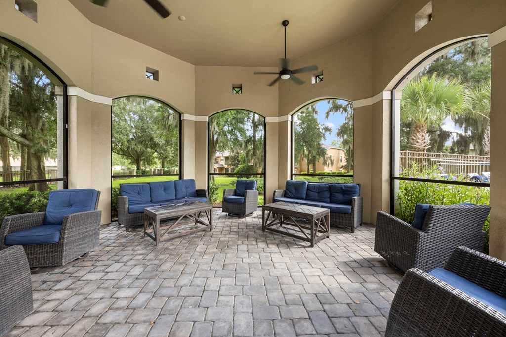 a covered patio with chairs and tables and large windows
