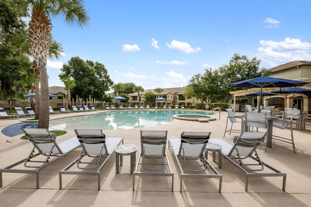 a swimming pool with chairs and umbrellas next to a resort style pool