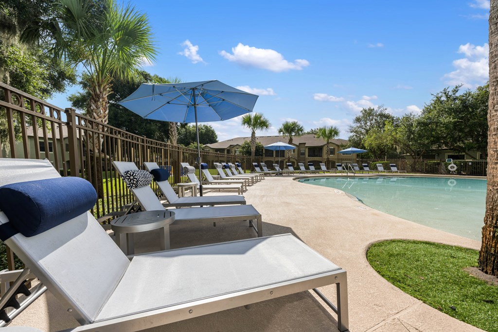 a pool with lounge chairs and umbrellas next to a pool