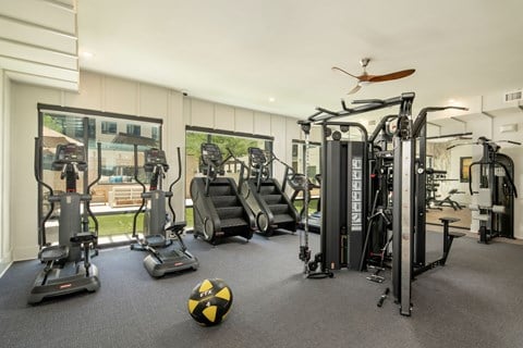 A gym with a variety of equipment including treadmills, elliptical machines, and a weight machine.