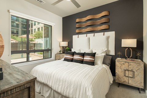 A bedroom with a large bed and a window overlooking a cityscape.