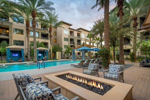 A poolside area with a fire pit and lounge chairs.