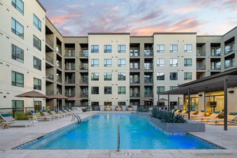 A large swimming pool in front of apartment buildings.