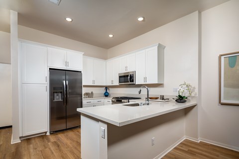 A kitchen with white cabinets and a stainless steel refrigerator.