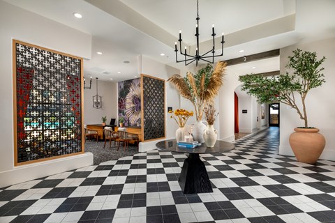 A black and white checkered floor in a room with a large painting and a tall vase.