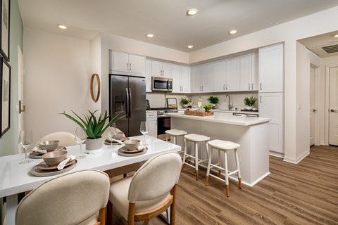 A modern kitchen with a dining table set for two.