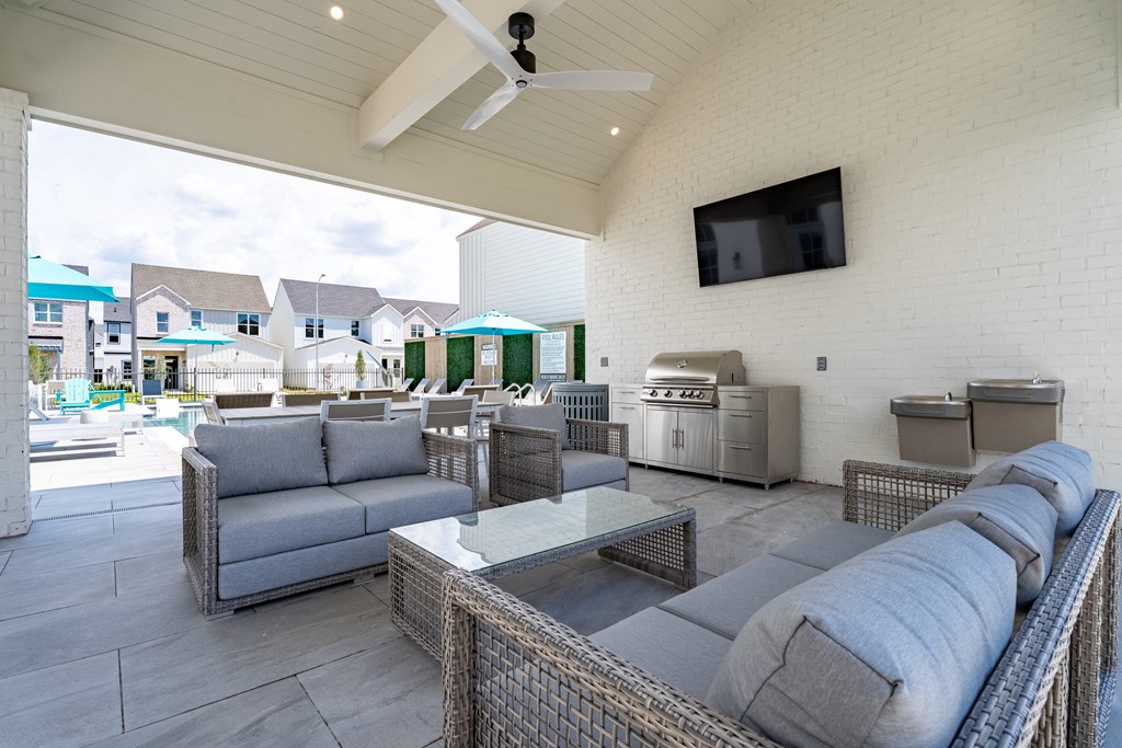 A patio with grey furniture and a television mounted on the wall.