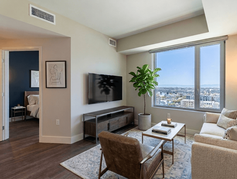 A living room with a brown chair, a white coffee table, and a large window overlooking the city.