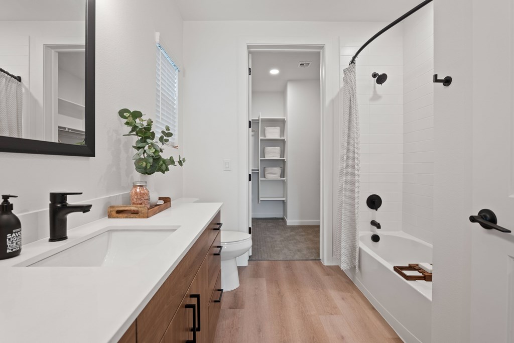 A white bathroom with a sink, mirror, and bathtub.