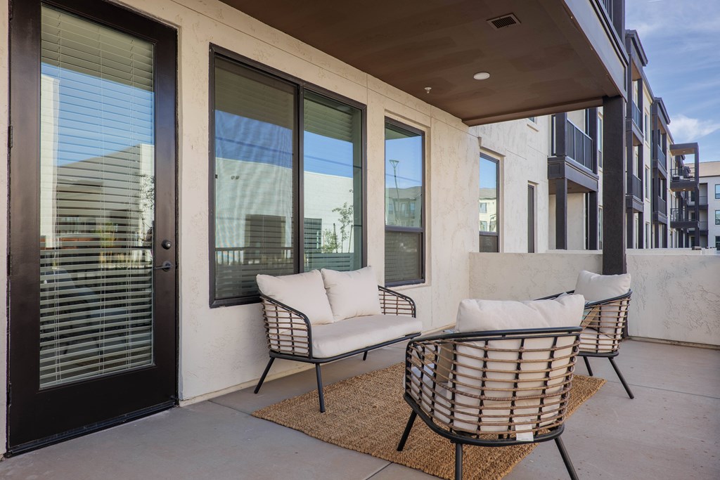 A patio with a white couch and two chairs.