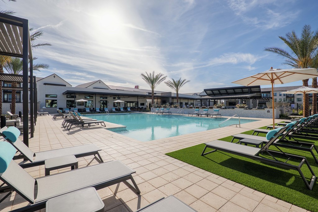 A sunny day at the poolside with lounge chairs and umbrellas.
