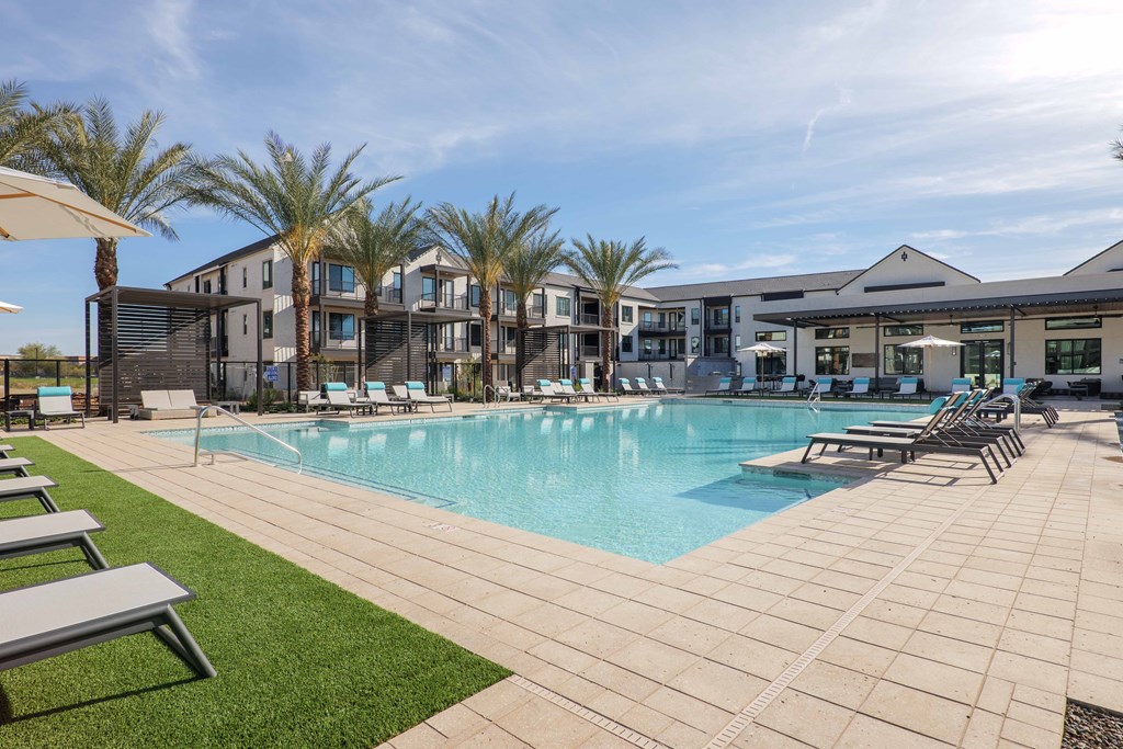 A large swimming pool surrounded by lounge chairs and palm trees.
