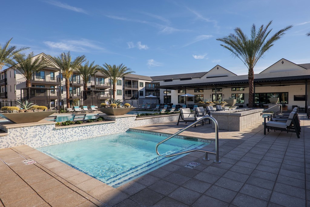 A swimming pool surrounded by palm trees and lounge chairs.