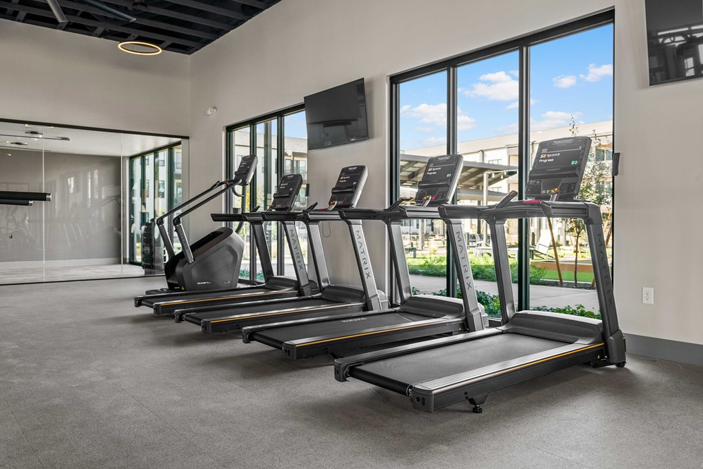 A gym with treadmills and a television.