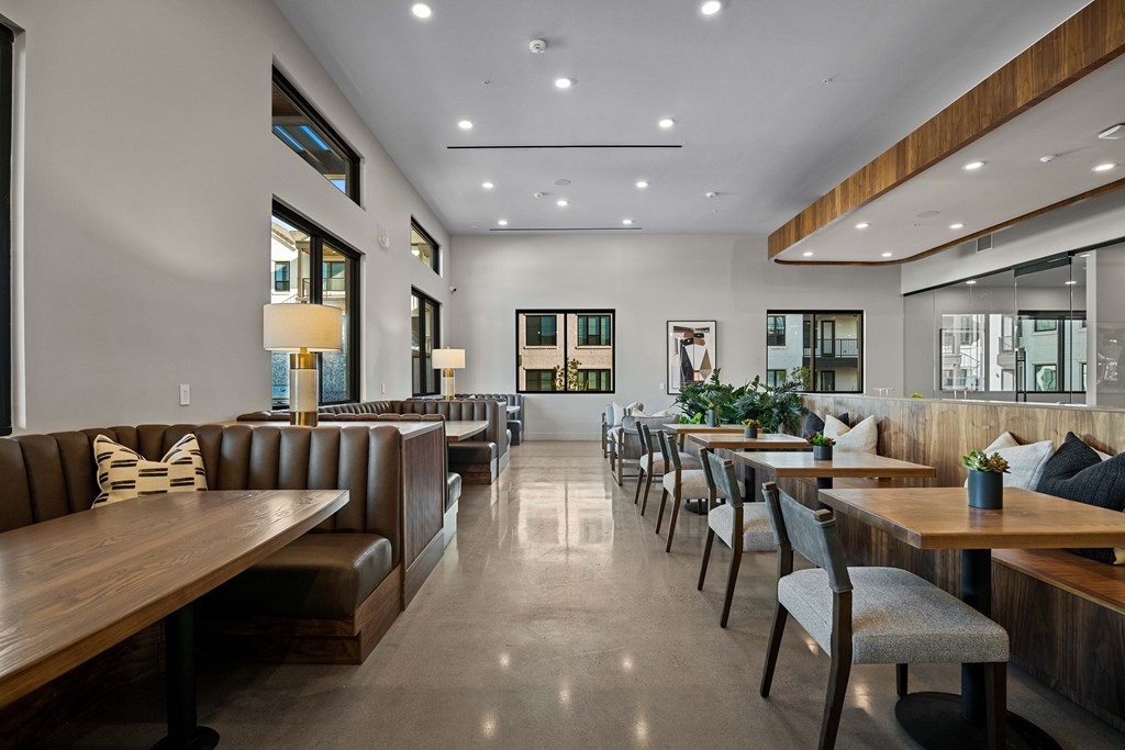 A long wooden table is surrounded by chairs in a modern restaurant.