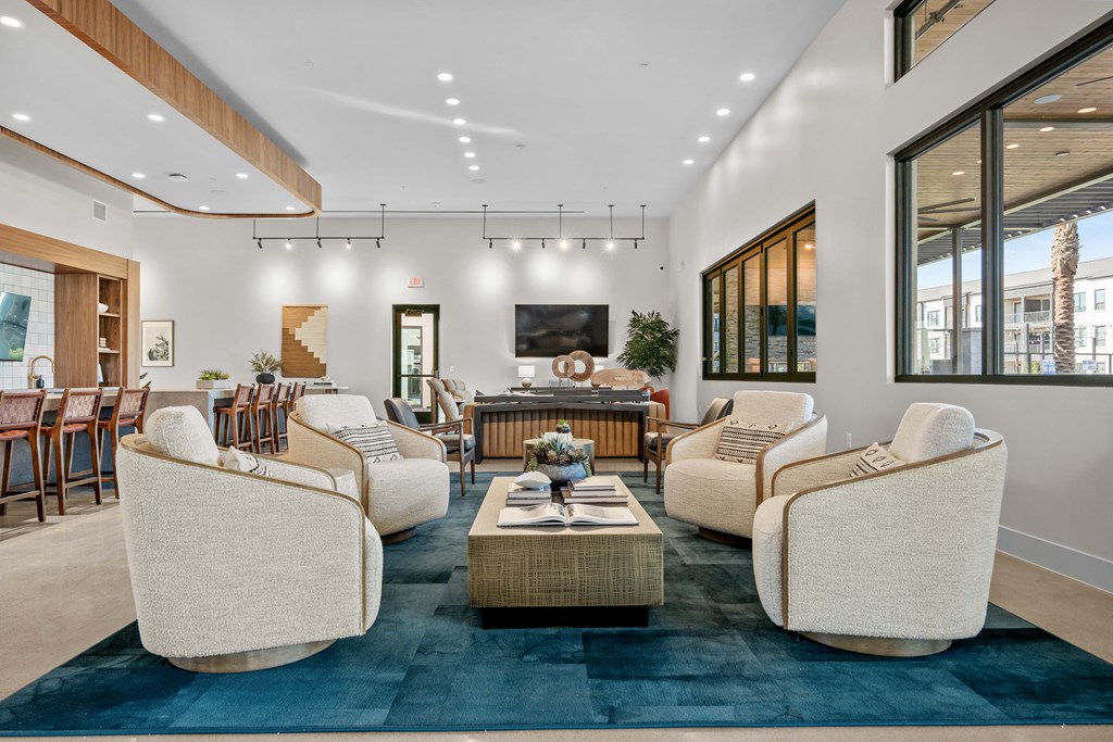 A living room with a blue rug and white chairs.