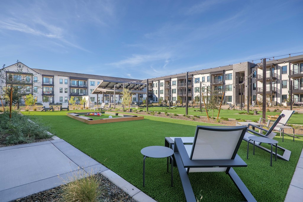 A modern outdoor seating area with a table and chairs in front of apartment buildings.