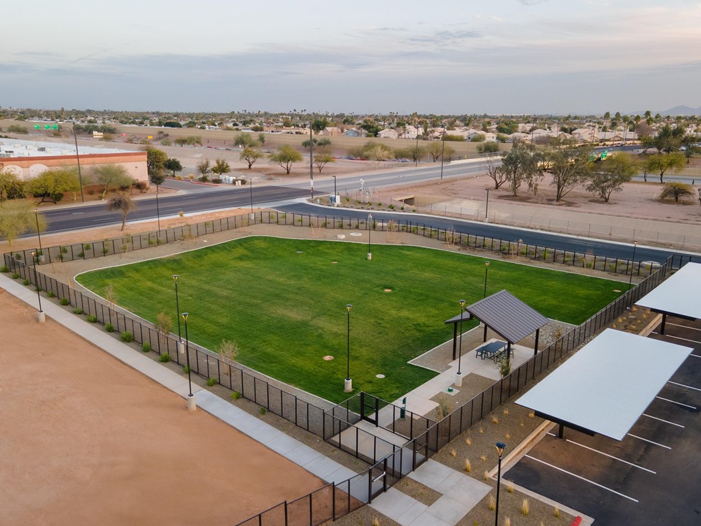 A large, open, fenced-in area with a grassy field and a covered seating area.