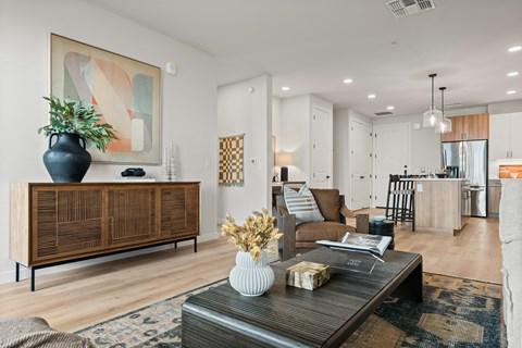 A living room with a wooden cabinet and a coffee table with a vase and a plant on it.
